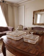 Two square crystal dry fruit dishes with textured patterns and gold trim, displayed in medium and large sizes on a wooden table.