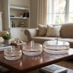 Three elegant cut-crystal dry fruit dishes with gold rims and matching spherical-handle lids displayed in Small, Medium, and Large sizes on a wooden coffee table in a modern living room.