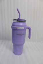 A row of colorful 1.5L stainless steel tumblers with handles and straws arranged on a kitchen counter.