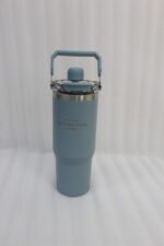 An assortment of colorful 900ml stainless steel tumblers with handles and transparent straw lids arranged neatly on a kitchen counter.