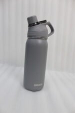 Four Dodge 630mL stainless steel water bottles in black, sage green, grey, and beige lined up on a kitchen counter.