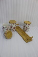 Three floral print ceramic storage jars with bamboo lids arranged on a matching wooden tray on a modern kitchen countertop