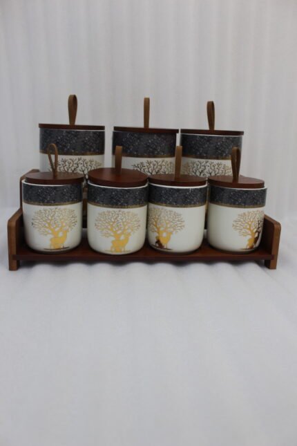 Luxury ceramic kitchen jar set with golden tree and deer patterns, wooden lids with loop handles, and a matching wooden display stand on a kitchen countertop.