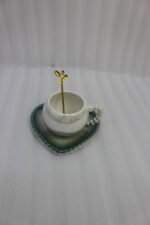 Elegant pastel ceramic cup and saucer set with a matching gold spoon and beaded handle on a marble kitchen countertop.