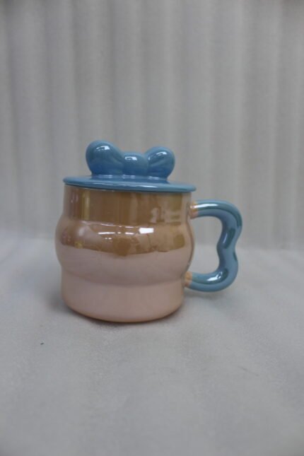 Four pastel ceramic mugs with matching lids and cute bow details, featuring a glossy pearl finish arranged on a marble kitchen countertop.