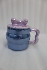 Four pastel ceramic mugs with matching lids and cute bow details, featuring a glossy pearl finish arranged on a marble kitchen countertop.