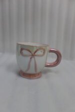 Four pastel ceramic coffee mugs with cute raised bows and matching colorful bases arranged on a marble kitchen counter.