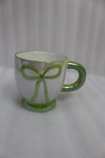 Four pastel ceramic coffee mugs with cute raised bows and matching colorful bases arranged on a marble kitchen counter.