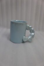 Four colorful ceramic mugs with unique bubble-textured handles arranged on a marble kitchen countertop.