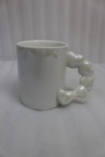 Four colorful ceramic mugs with unique bubble-textured handles arranged on a marble kitchen countertop.