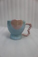 Four colorful ceramic mugs featuring heart accents and beaded handles lined up on a kitchen counter.