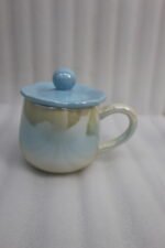 Four colorful pastel ceramic mugs with matching lids featuring sphere knobs, arranged neatly on a marble kitchen countertop with cinematic lighting