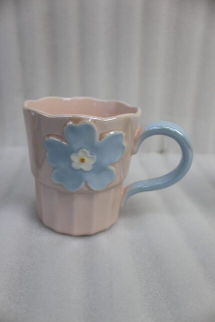 Four pastel ceramic coffee mugs with 3D floral designs lined up on a kitchen counter with cinematic lighting.