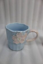 Four pastel ceramic coffee mugs with 3D floral designs lined up on a kitchen counter with cinematic lighting.
