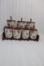 Floral ceramic kitchen canister and jar set with wooden lids and display stand on a kitchen counter