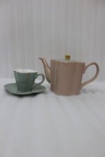 Pink and pastel ceramic tea set featuring 6 cups, 1 kettle, and a stacked saucer tier organized on a wooden display stand and tray on a kitchen counter.