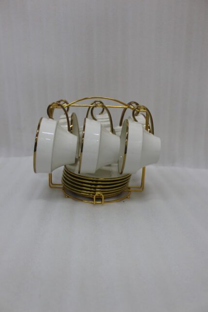White ceramic tea cups and saucers neatly organized on a luxury golden stand on a marble kitchen countertop.