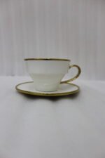 White ceramic tea cups and saucers neatly organized on a luxury golden stand on a marble kitchen countertop.