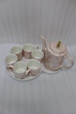 Luxury iridescent ceramic tea set with 6 cups, kettle, white ceramic tray, and golden display stand on a kitchen counter.