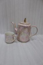 Luxury iridescent ceramic tea set with 6 cups, kettle, white ceramic tray, and golden display stand on a kitchen counter.