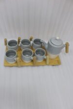 A stylish ceramic tea set in grey and white with wooden-style handles, consisting of six cups and one kettle, neatly arranged on a wooden tray display.