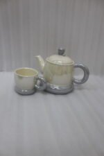 Ceramic rotating tray tea set with six cups and a kettle arranged neatly on a modern kitchen countertop.