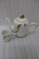 White and gold ceramic tea set with 6 cups, 1 kettle, and a rotating tray displayed on a kitchen counter.