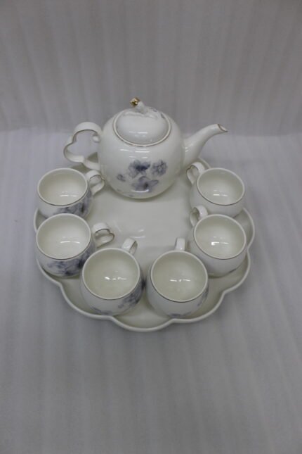 Elegant ceramic tea set featuring 6 floral-patterned cups, 1 kettle, and a wooden rotating tray on a modern kitchen countertop.