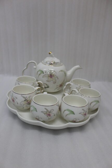 Elegant floral ceramic tea set featuring one kettle, six matching cups, and a smooth rotating tray on a kitchen counter.