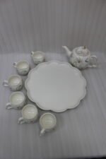 Elegant floral ceramic tea set featuring one kettle, six matching cups, and a smooth rotating tray on a kitchen counter.