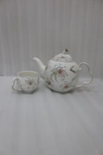 Elegant floral ceramic tea set featuring one kettle, six matching cups, and a smooth rotating tray on a kitchen counter.