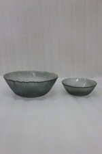 Two grey ribbed glass bowls with gold trim displayed together on a modern white marble countertop