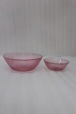 Two grey ribbed glass bowls with gold trim displayed together on a modern white marble countertop