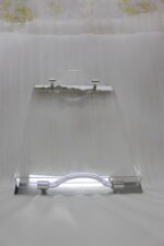 Clear acrylic serving tray set with polished handles displayed on a marble countertop in a modern kitchen setting