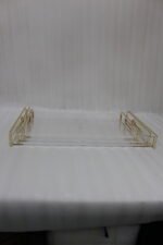 Nesting clear acrylic serving tray set with polished gold handles displayed on a white marble kitchen countertop.