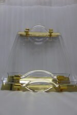 Luxurious clear acrylic serving tray set with polished gold handles and curved design, displayed on a marble countertop in a modern kitchen