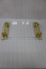 Luxurious clear acrylic serving tray set with polished gold handles and curved design, displayed on a marble countertop in a modern kitchen