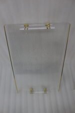 A nested set of clear ribbed acrylic serving trays with elegant gold handles and accents, displayed on a modern marble kitchen countertop next to glass spice jars.