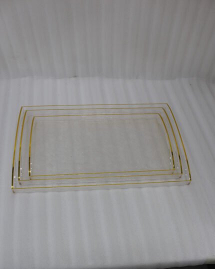 Nesting clear acrylic serving tray set with elegant gold trim and built-in handles, displayed on a modern kitchen countertop.