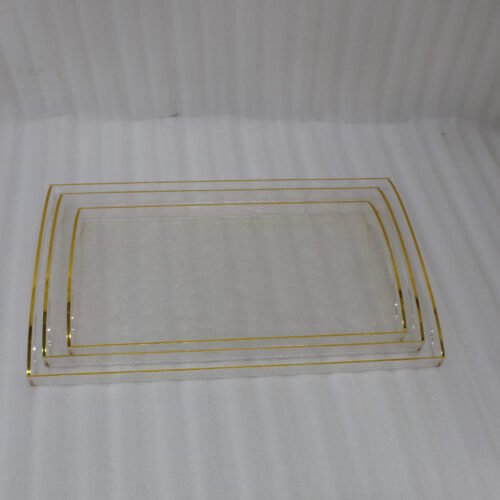 Nesting clear acrylic serving tray set with elegant gold trim and built-in handles, displayed on a modern kitchen countertop.