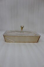 Elegant partitioned glass dry fruit dish with a gold trim and crystal-accented lid sitting on a wooden coffee table in a modern living room.