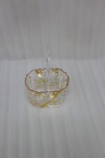 Clear acrylic spoon holder and cutlery caddy with gold accent patterns and a heart-shaped handle on a kitchen countertop holding utensils.