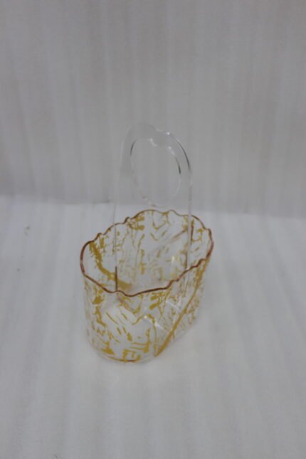 Clear acrylic spoon holder and cutlery caddy with gold accent patterns and a heart-shaped handle on a kitchen countertop holding utensils.