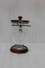 Set of three clear acrylic jars of varying sizes with wooden bases, wooden lids, airtight metal clamps, and hanging acrylic spoons on a kitchen countertop.