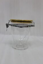 Three clear luxury acrylic storage jars of varying sizes featuring gold lids and secure silver airtight locking clasps, arranged on a marble countertop in a modern kitchen.
