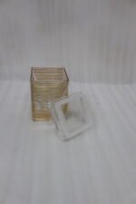 A set of three clear acrylic storage jars with decorative ribbed gold detailing, displayed neatly on a modern kitchen countertop.
