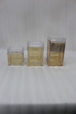 Three varying heights of clear ribbed acrylic storage jars with lids arranged on a modern kitchen countertop.
