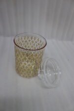Three clear acrylic storage jars of varying heights featuring a decorative gold pattern and matching lids, displayed on a kitchen countertop next to spices.