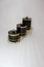 Luxury 3-piece black and gold ceramic storage jar set with golden lids arranged on an elegant gold metal cart stand on a modern kitchen countertop.
