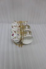 Luxury ceramic tea set with 6 floral cups, matching saucers, and a golden stand on a kitchen counter.